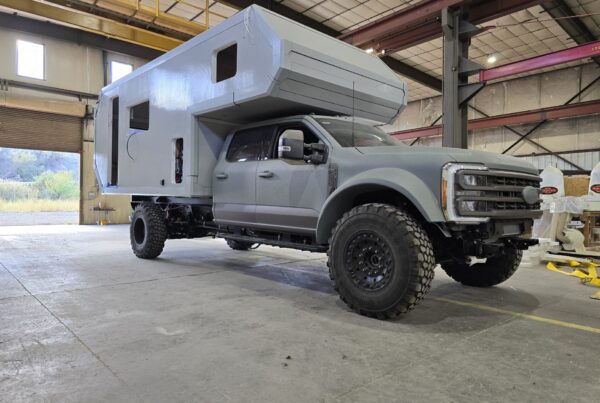 Gay pickup with gray camper in a large warehouse