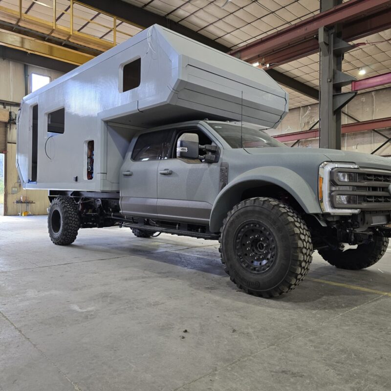 Gay pickup with gray camper in a large warehouse