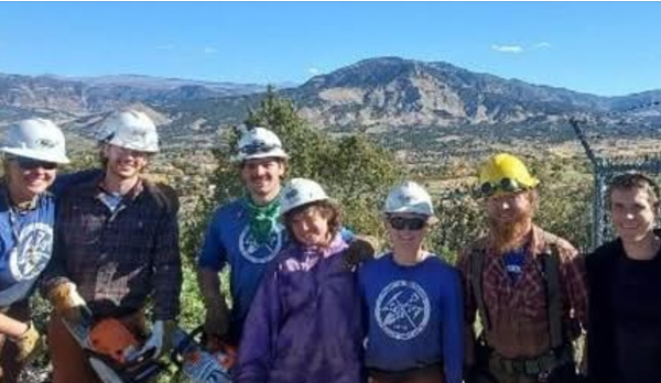 A group of people wearing hard hats in front of a mountain