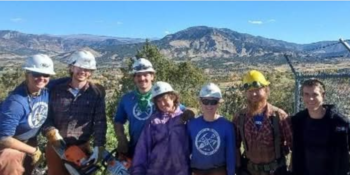 A group of people wearing hard hats in front of a mountain