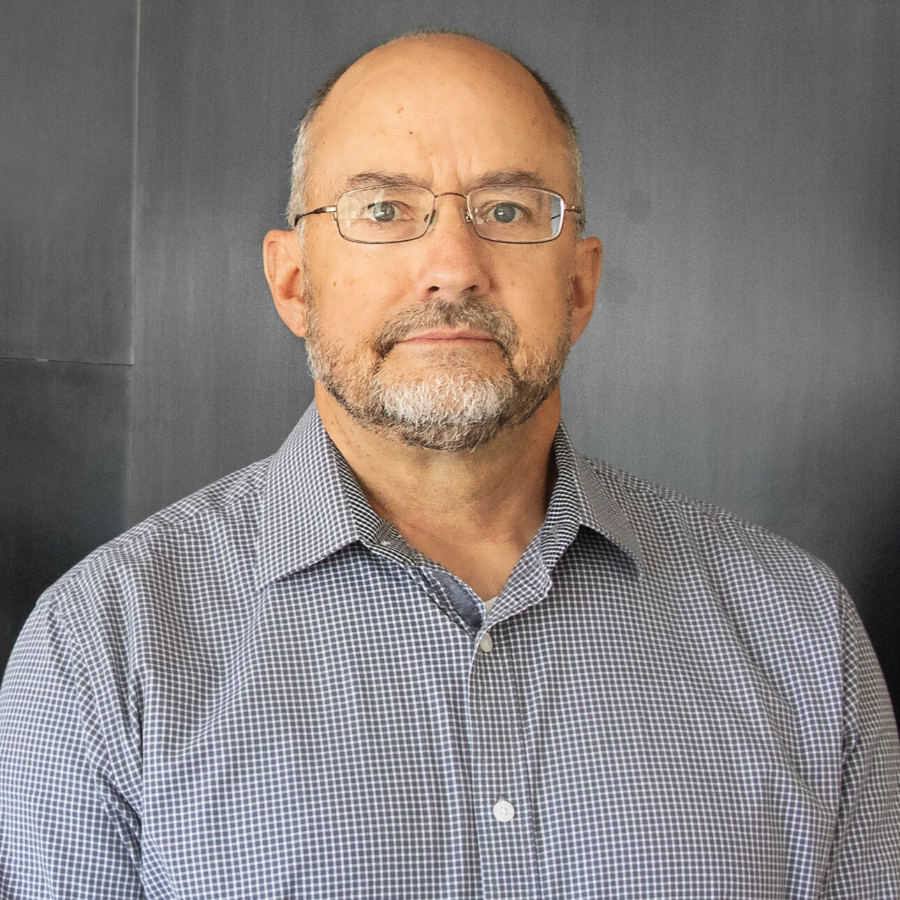 Man wearing a gray shirt and glasses in front of a gray background