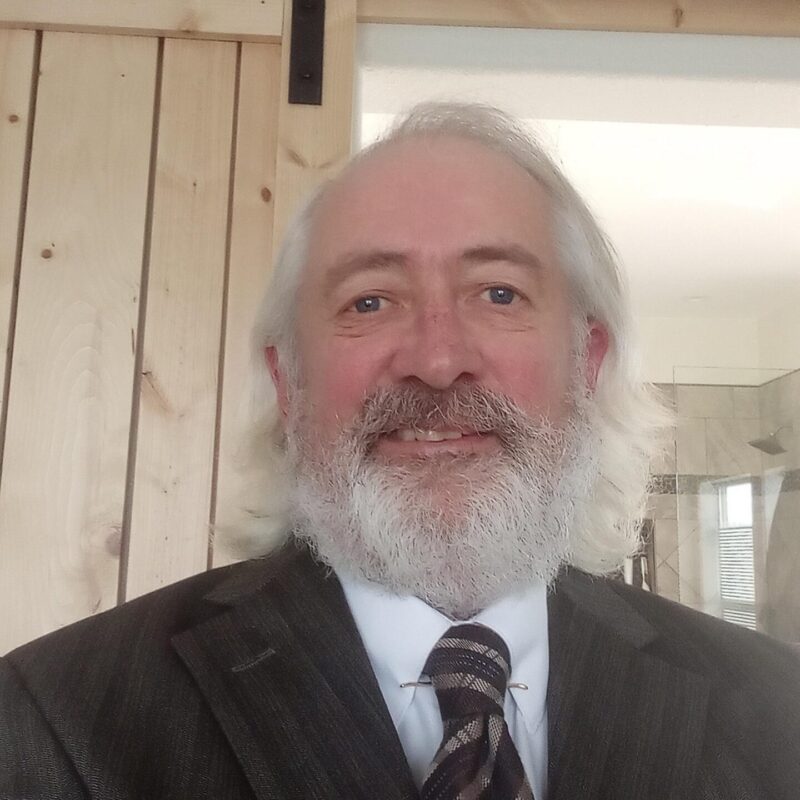 Man with a brown suit and striped tie, white hair and a beard